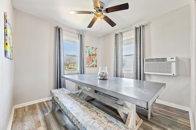 dining space featuring an AC wall unit, baseboards, and wood finished floors