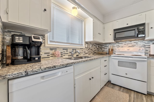 kitchen with light wood finished floors, decorative backsplash, white cabinets, white appliances, and a sink