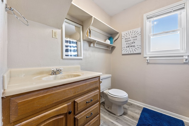 bathroom featuring toilet, vanity, baseboards, and wood finished floors