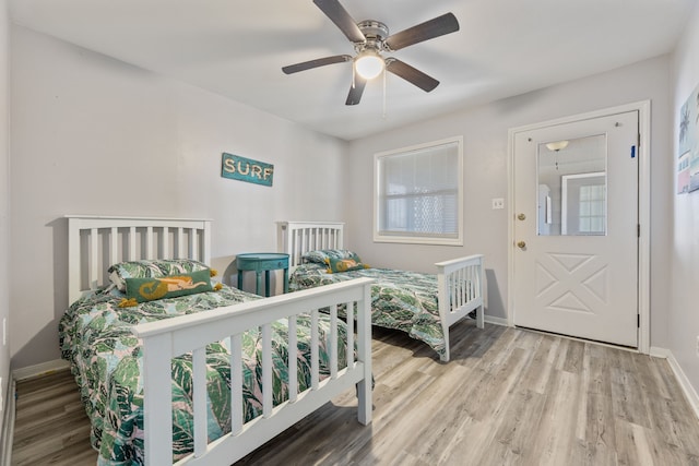 bedroom featuring baseboards, wood finished floors, and a ceiling fan