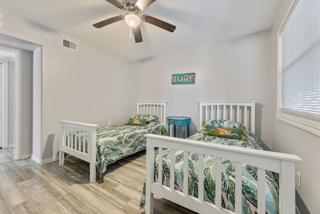 bedroom with visible vents, baseboards, wood finished floors, and a ceiling fan