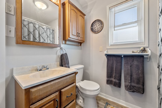 bathroom with baseboards, toilet, wood finished floors, and vanity