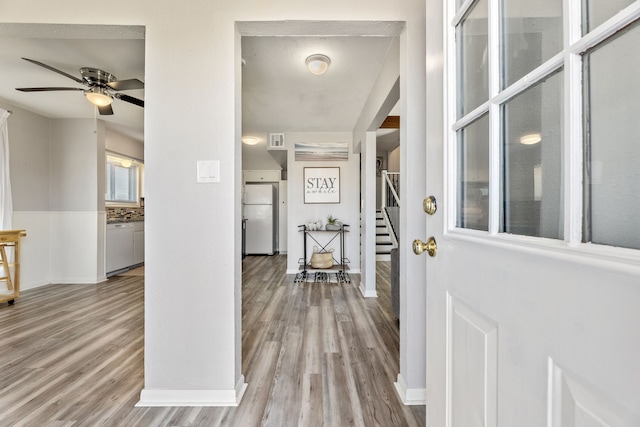 foyer featuring visible vents, wood finished floors, baseboards, ceiling fan, and stairs