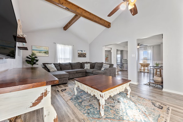 living room featuring a wealth of natural light, beamed ceiling, high vaulted ceiling, and wood finished floors