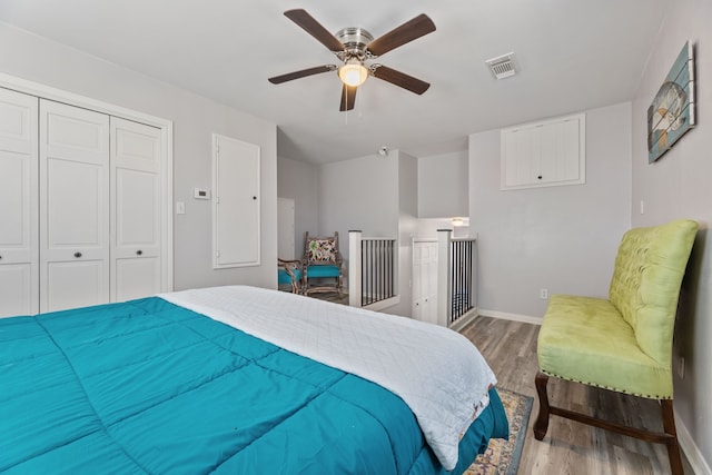 bedroom with a closet, visible vents, baseboards, and wood finished floors