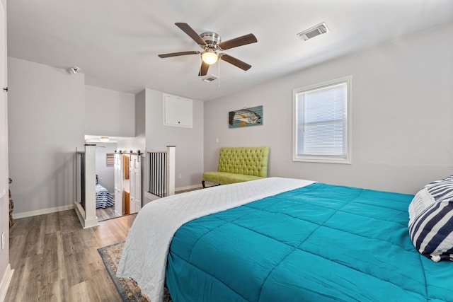 bedroom featuring visible vents, baseboards, wood finished floors, and a ceiling fan