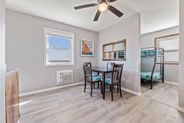 dining space featuring a wall mounted air conditioner, baseboards, wood finished floors, and ceiling fan