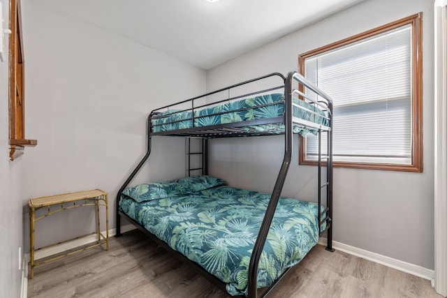 bedroom featuring multiple windows, baseboards, and wood finished floors