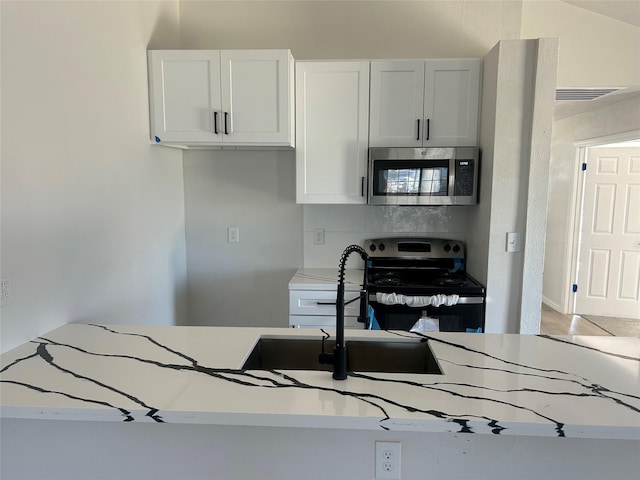 kitchen with stainless steel appliances, white cabinetry, visible vents, and light countertops