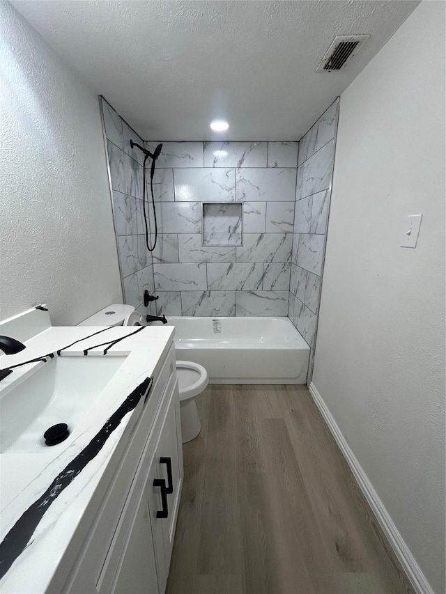 full bath with wood finished floors, visible vents, baseboards, a textured ceiling, and toilet