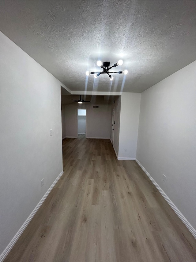 unfurnished room with baseboards, a textured ceiling, and wood finished floors