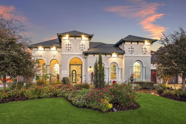 view of front of house featuring stucco siding and a yard