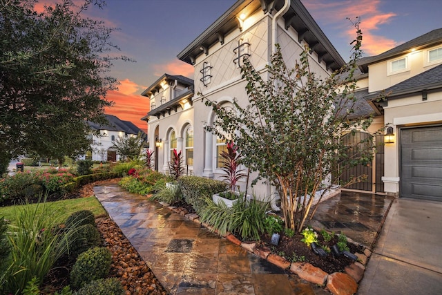 exterior space with a gate, a garage, and stucco siding