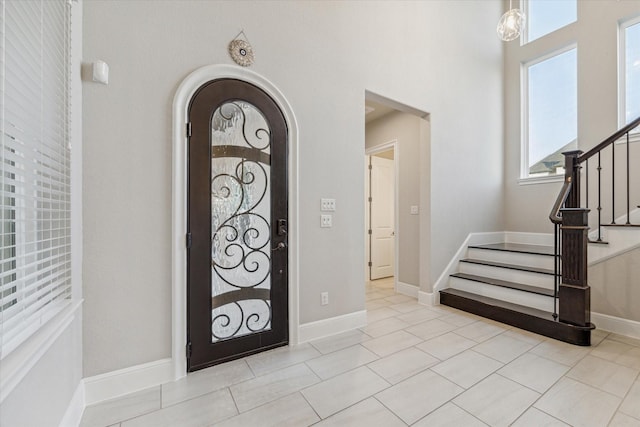 entrance foyer with tile patterned floors, stairs, and baseboards