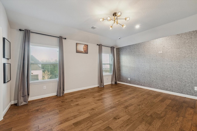 spare room with visible vents, plenty of natural light, and wood finished floors