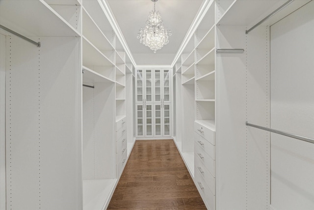 spacious closet featuring dark wood finished floors and an inviting chandelier