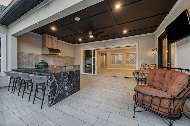 exterior space with outdoor wet bar, exterior kitchen, a ceiling fan, and a sink