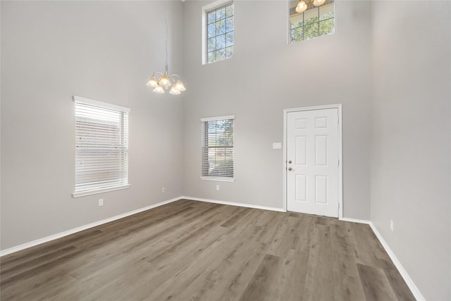 entryway with a wealth of natural light, a chandelier, baseboards, and wood finished floors