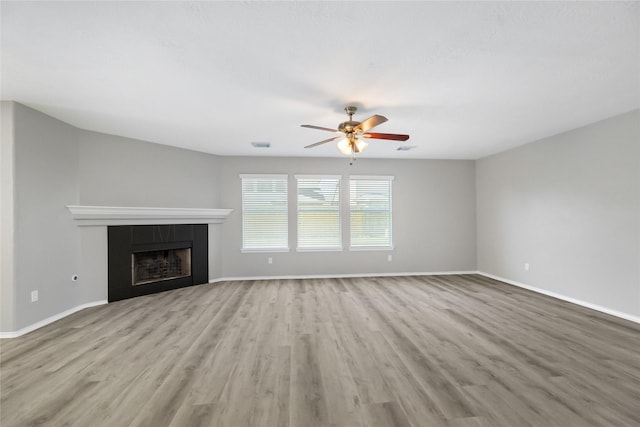 unfurnished living room with visible vents, baseboards, wood finished floors, and a tiled fireplace