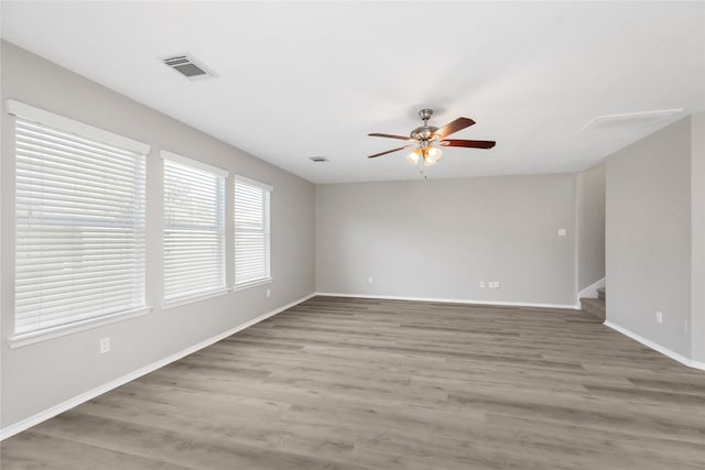 empty room with stairs, baseboards, visible vents, and light wood finished floors