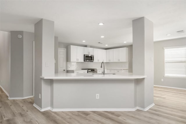 kitchen featuring a sink, stainless steel appliances, white cabinets, light countertops, and decorative backsplash