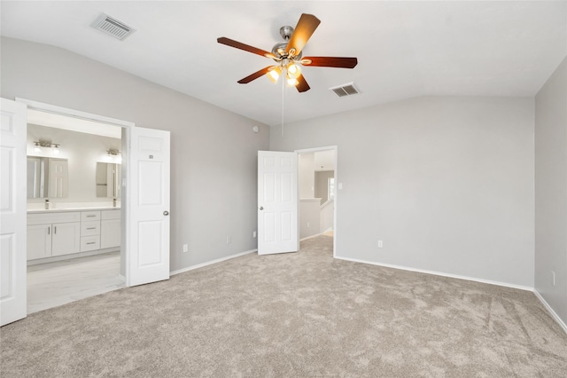 unfurnished bedroom with lofted ceiling, visible vents, ensuite bathroom, and light carpet