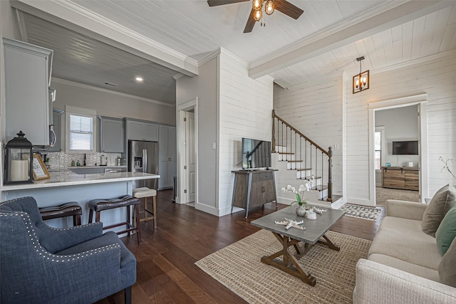 living area featuring wooden walls, crown molding, stairway, beam ceiling, and dark wood-style flooring