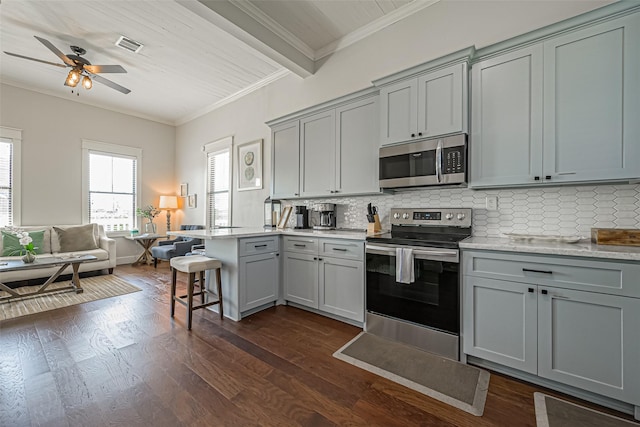 kitchen with a kitchen bar, gray cabinets, and appliances with stainless steel finishes