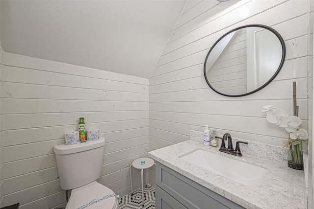 half bathroom featuring wooden walls, lofted ceiling, toilet, and vanity