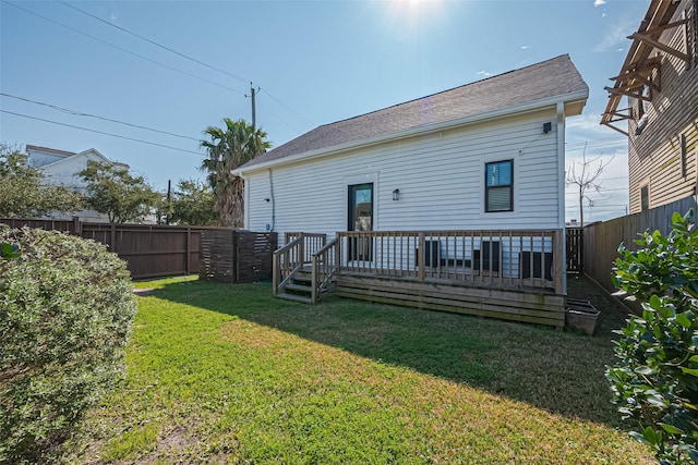 rear view of house featuring a deck, a lawn, and a fenced backyard