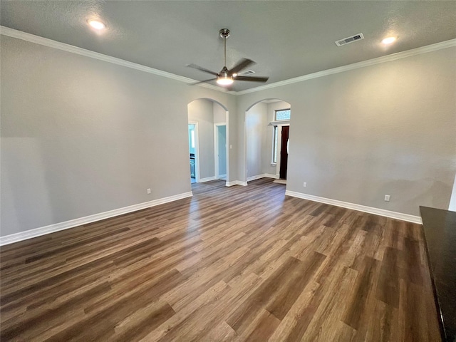 empty room featuring visible vents, dark wood-style floors, arched walkways, baseboards, and ceiling fan