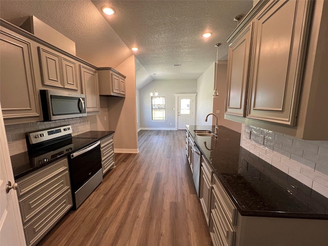 kitchen with tasteful backsplash, a sink, baseboards, appliances with stainless steel finishes, and dark wood-style flooring