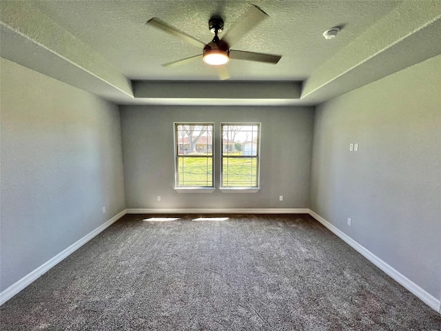 carpeted empty room featuring a tray ceiling, baseboards, a textured ceiling, and ceiling fan