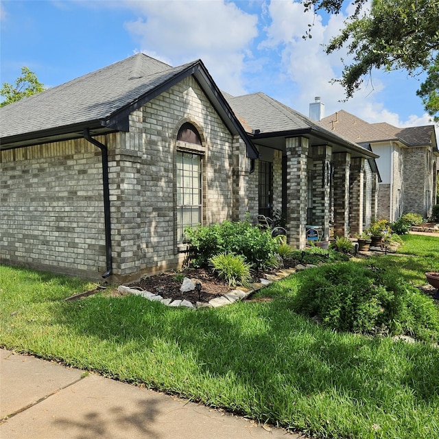 view of front of home with a shingled roof, brick siding, and a chimney