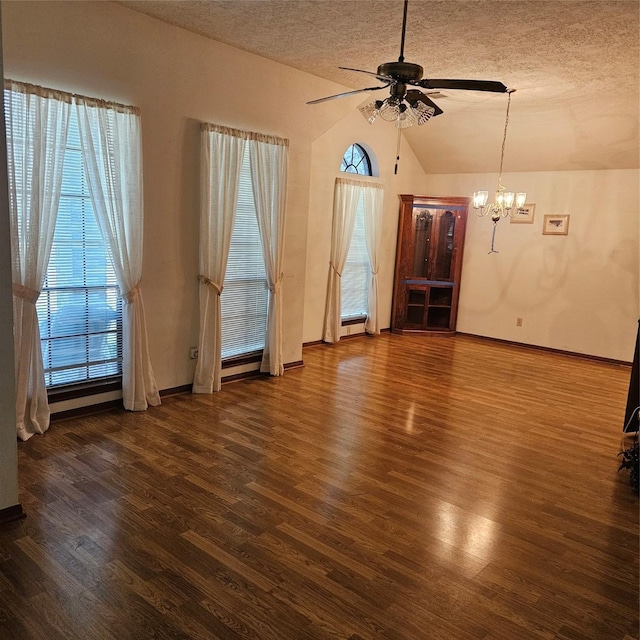 unfurnished living room featuring a healthy amount of sunlight, a textured ceiling, dark wood-type flooring, and vaulted ceiling