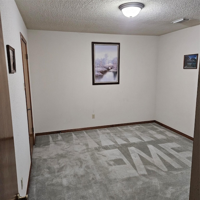 carpeted empty room featuring a textured ceiling and baseboards