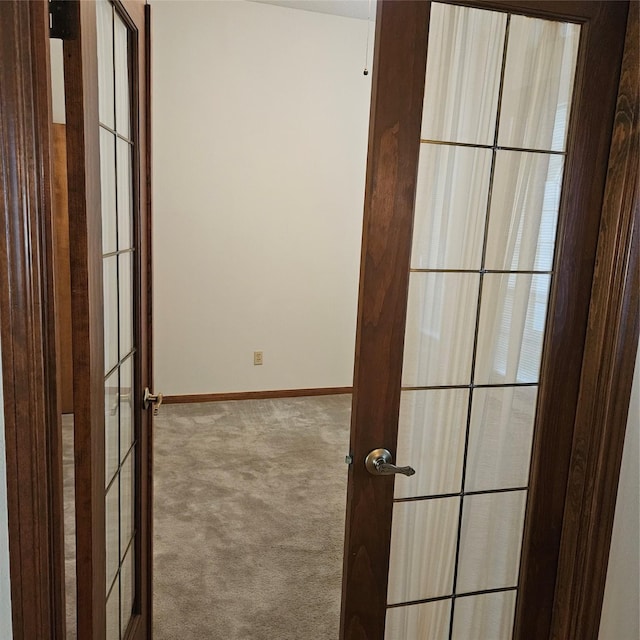 hallway featuring french doors, baseboards, and carpet flooring