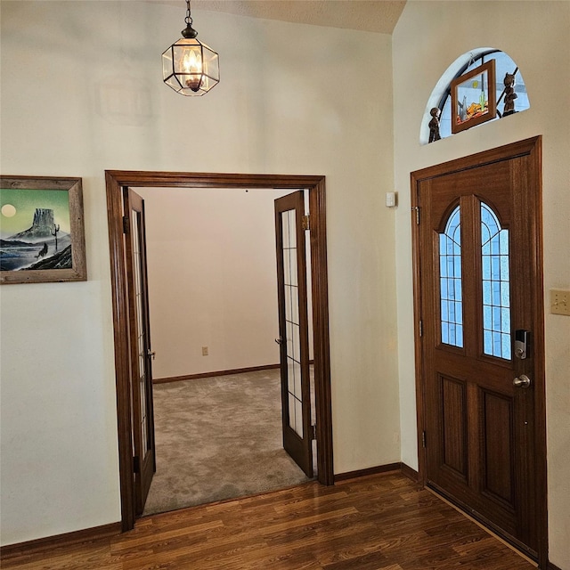 entrance foyer with a towering ceiling, dark wood-style floors, baseboards, and french doors