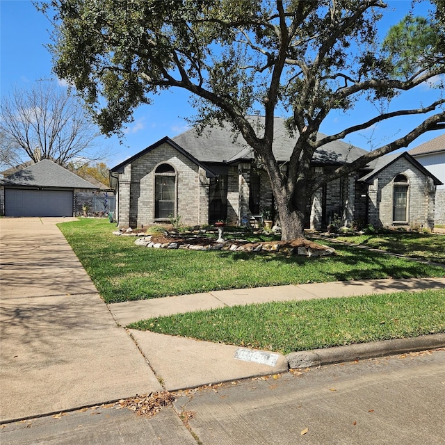 view of front of property with a detached garage, brick siding, an outbuilding, and a front yard