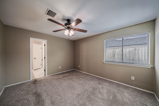 empty room with a ceiling fan, carpet flooring, baseboards, and visible vents