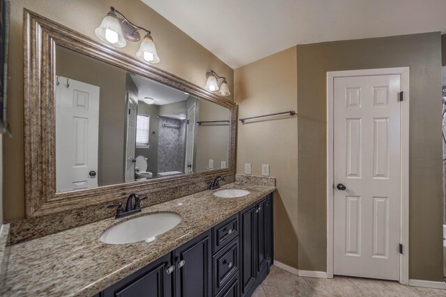 bathroom featuring double vanity, tile patterned floors, toilet, and a sink