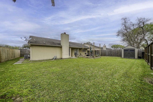 view of yard featuring an outbuilding, a fenced backyard, and a shed