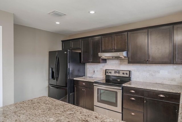 kitchen with visible vents, black fridge, under cabinet range hood, stainless steel range with electric cooktop, and decorative backsplash