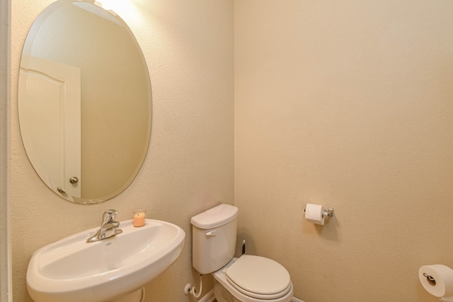 bathroom with a sink, baseboards, and toilet