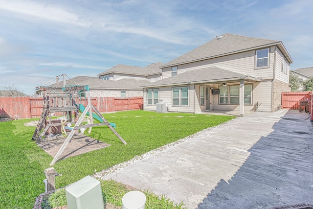 back of house featuring a yard, a fenced backyard, a playground, central air condition unit, and brick siding