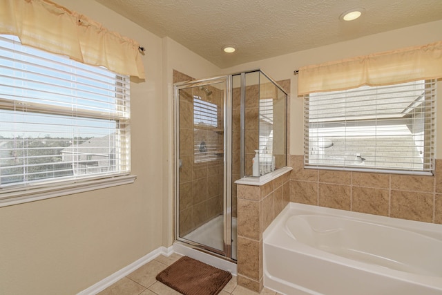 bathroom featuring tile patterned flooring, baseboards, a stall shower, a bath, and a textured ceiling