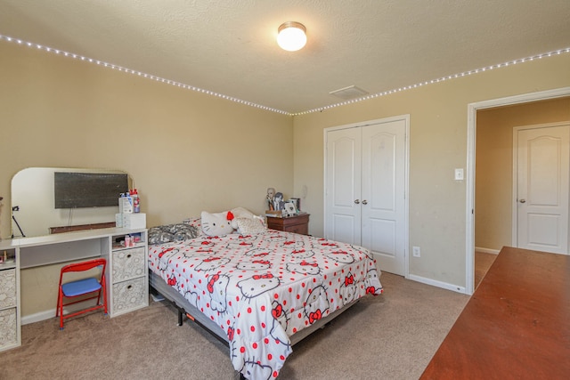 carpeted bedroom with a closet, baseboards, a textured ceiling, and visible vents