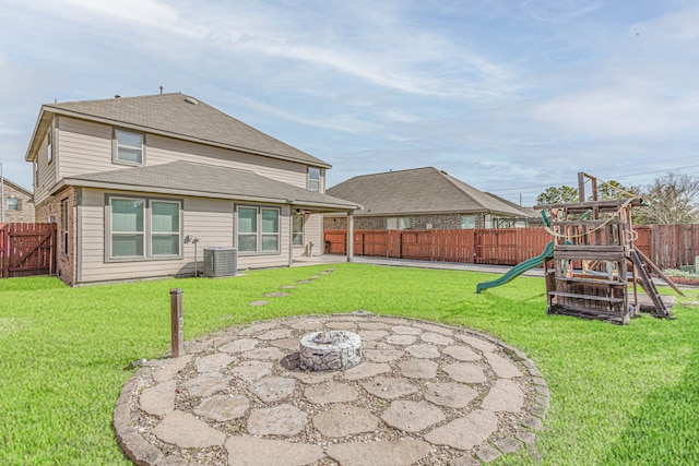 rear view of house with a fire pit, a playground, a yard, a fenced backyard, and a patio area