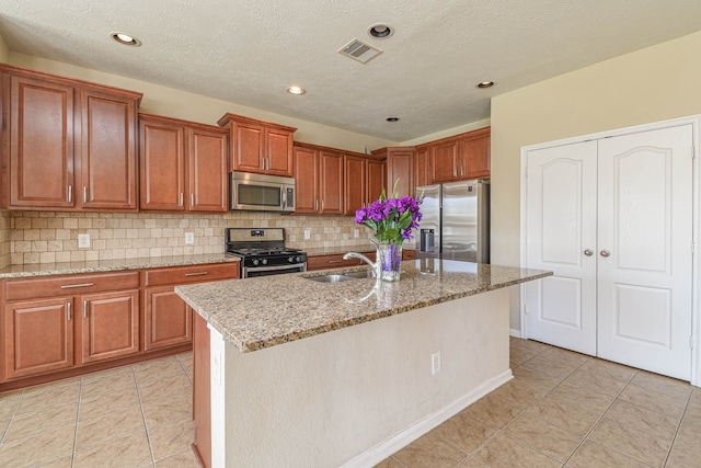 kitchen with a sink, brown cabinetry, visible vents, and stainless steel appliances