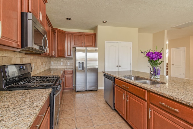 kitchen featuring light tile patterned floors, light stone countertops, a sink, stainless steel appliances, and tasteful backsplash